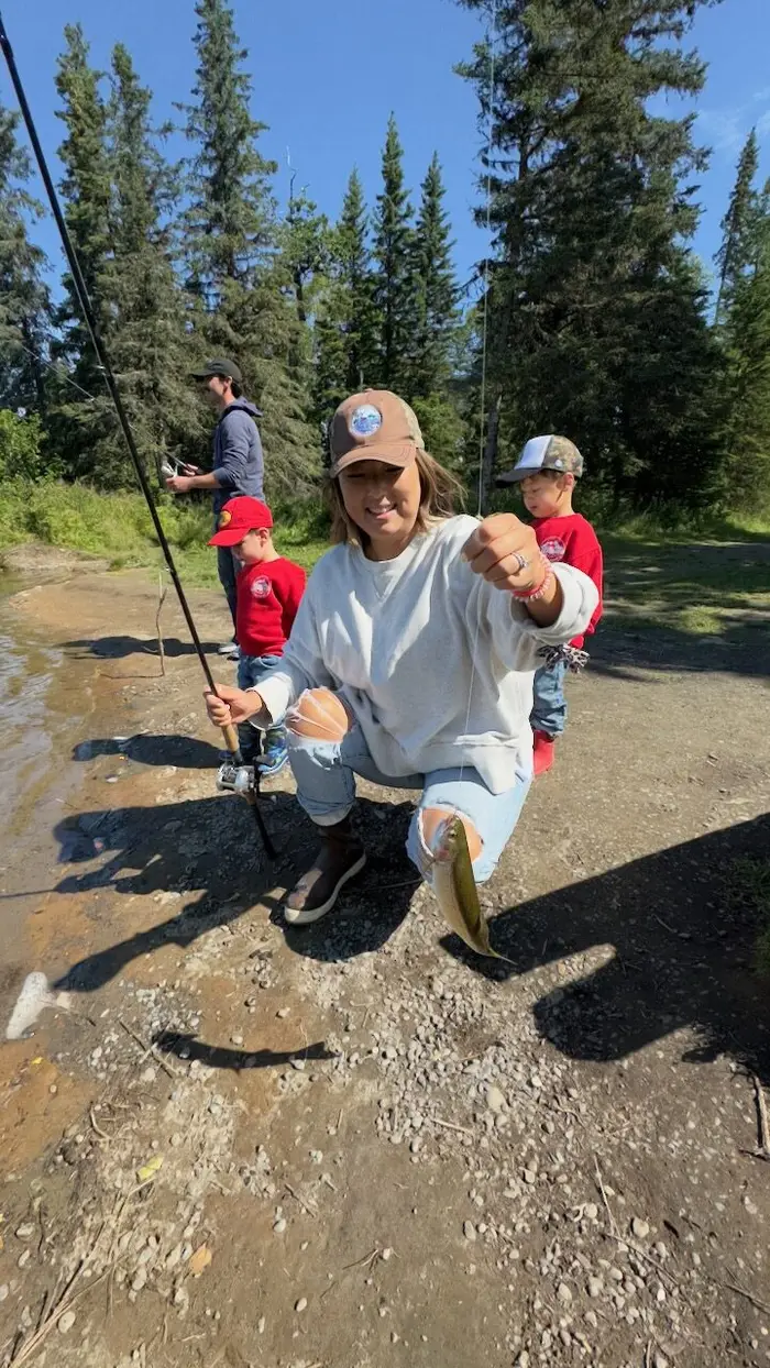 A dad and his kids playing with the fishing poles by the water