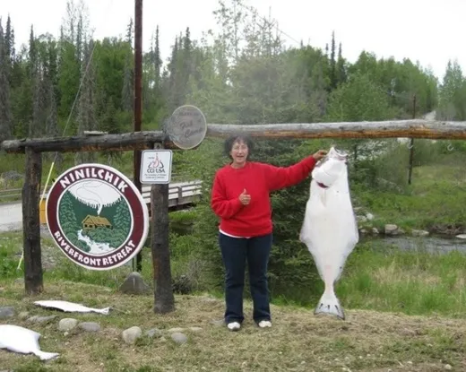 Group posing with a caught salmon on a dock or ramp.