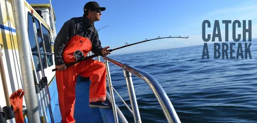 Guest on a boat holding up a large catch over open water.