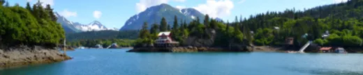 Panoramic view of the inlet with mountains reflected in calm water.