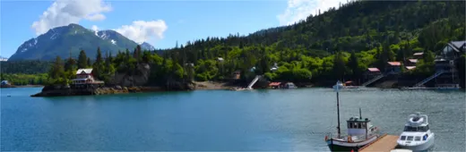 Calm inlet with mountain rising beyond the shoreline.
