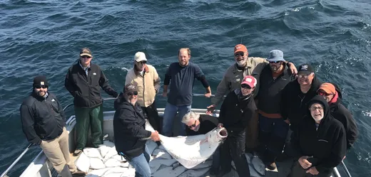 Smiling group of anglers posed together on the boat.