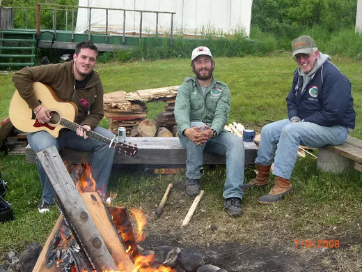 Small group relaxing together at an outdoor table at the camp.