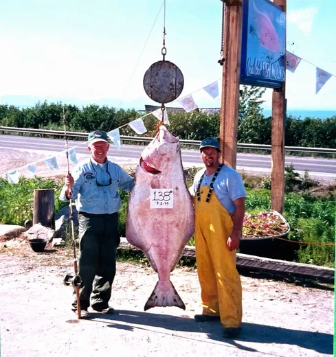 Guest holds up a large halibut at the dock.