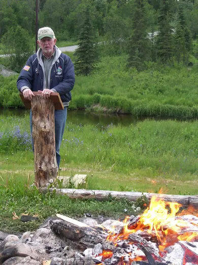 Campfire cookout with fish grilling outdoors.