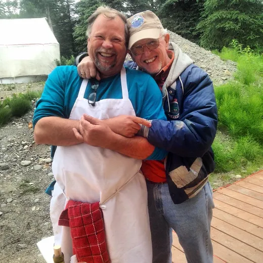 Two guests embrace and smile for a camp photo.