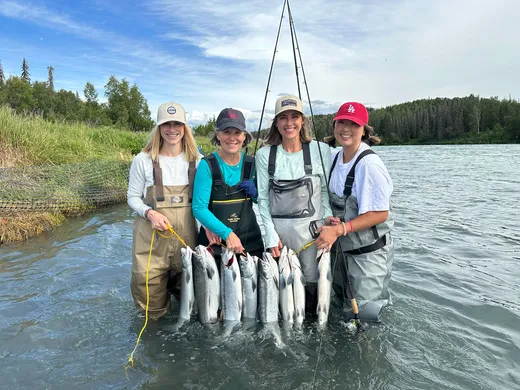 Group of anglers holding a salmon haul in the river