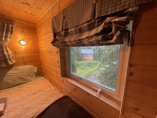 Interior view of a cabin room with wood-paneled walls and window light.