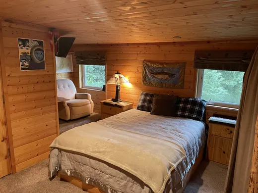 Cozy cabin bedroom with wood walls and a neatly made bed.