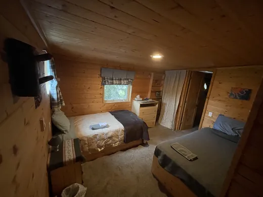 Cabin bedroom interior with warm wood tones and window.