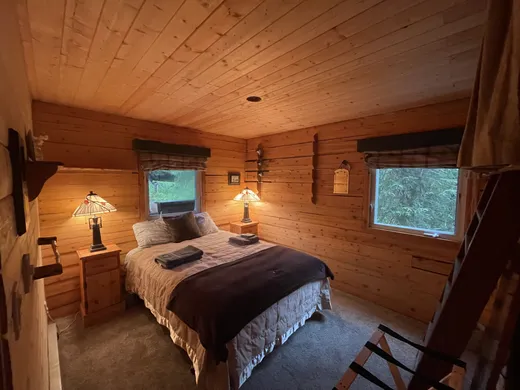 Cabin bedroom with twin beds and wood-paneled walls.