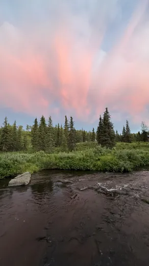 Pink sunset sky over a winding river through the tundra.