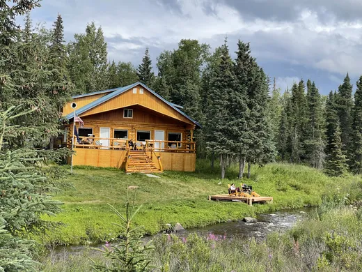 Exterior of a small cabin nestled among spruce trees.