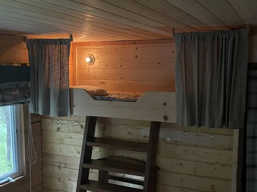 Cabin bedroom with bunk beds and wood-paneled walls.
