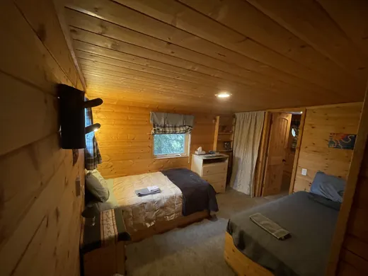 Cabin bedroom with bed and wood walls in warm light.